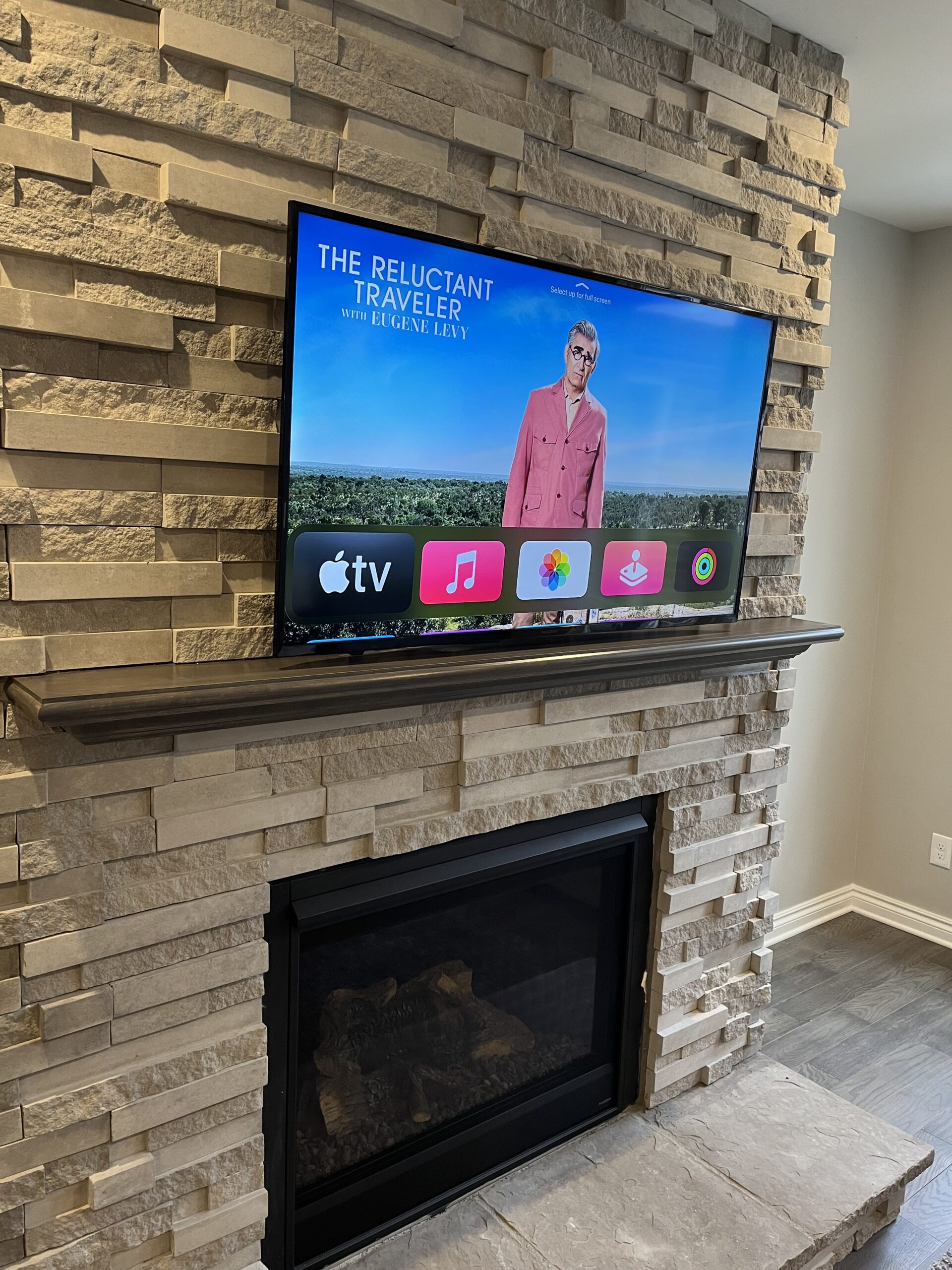 Professionally mounted television above a stone fireplace